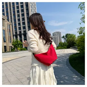 Bolso de hombro rojo informal llevado por modelo al aire libre, estilo diario elegante.