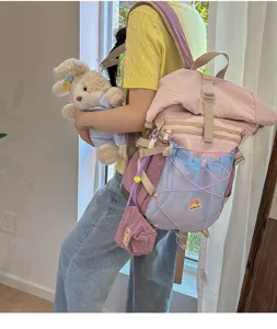Detail view of a stylish college style roll top student backpack with multi pockets and plush toy.