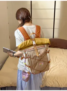 Detail view of the colorful roll-top student backpack in the bedroom scene setup.