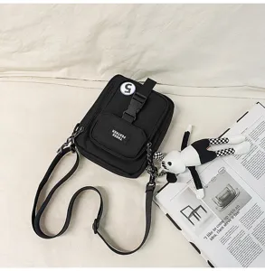 Primer plano detallado de un bolso bandolera informal de lona negra con hebilla y bolsillo.