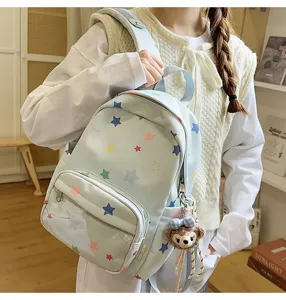Vista detallada de la mochila azul claro con estampados de estrellas y colgante de peluche.