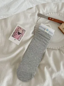 Detailed view of gray mid-calf slouch socks featuring light blue ribbed cuffs and tag.