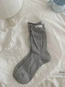 Korean style grey hollow mid-tube cotton socks with cute rolled cuffs and fabric label details.