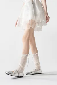 Transparante kanten beenwarmers in balletstijl met strik en zilveren platte schoenen.