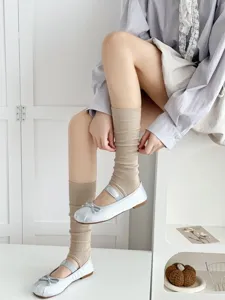 Detail shot of stylish stirrup socks paired with silver ballet flats in a clean indoor setting.