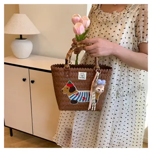 Borsa a mano intrecciata con manico in bambù, ricamo bassotto e ciondolo di peluche.