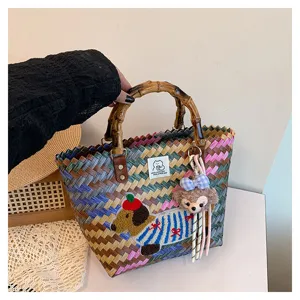 Borsa a mano intrecciata con manico in bambù, ricamo bassotto e ciondolo in peluche per le vacanze.