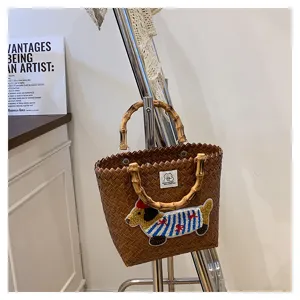 Vista dettagliata della borsa intrecciata retrò con manici in bambù e ricamo bassotto.