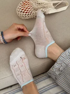 Close-up detail of women's sheer summer mesh boat socks with cute bow pattern and blue trim.