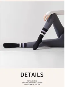 Primo piano di calzini da yoga lunghi neri con strisce viola e bianche durante la sessione.