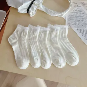 Vue détaillée de chaussettes mi-mollet blanches en maille avec motifs de nœuds ajourés.