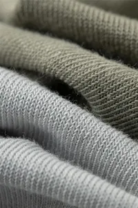 Nahaufnahme mit hohem Detailgrad zeigt weiche Baumwoll-Strickstoffstruktur und Stofffalten.