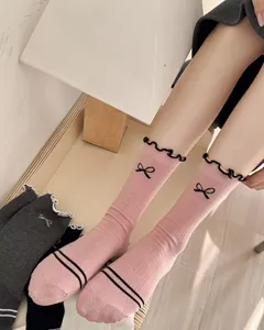 Detailed view of pink cotton mid-tube socks featuring cute bow embroidery and black ruffles.