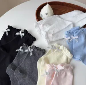 Feines Rüschenbündchen mit niedlichen Schleifchen an dünnen Baumwollsocken, saubere Nähte.