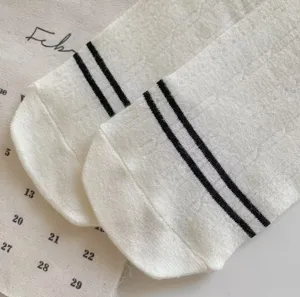 Detail shot of white cotton socks featuring stylish black double stripes at the cuff.