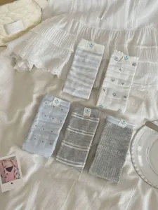 Detailed view of cute light-colored women mid tube socks with floral dot and stripe patterns.