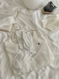 Korean sweet style hollow out cotton mid-calf socks with cute fabric label and roll cuff detail.