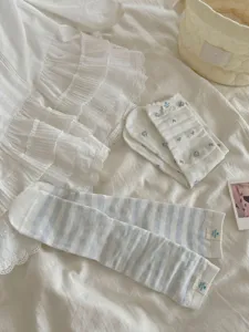 Detailed view of women's white ruffled socks and blue striped long socks on fabric.
