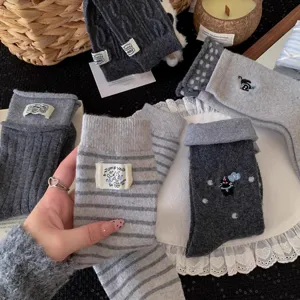 Close-up of grey wool socks featuring cute cat embroidery and woven label detail.