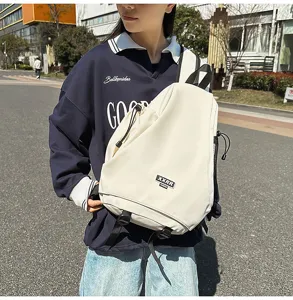 Dettaglio dello zaino in tela stile urbano, con colore chiaro, spallacci e toppa frontale.