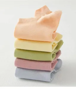 Primo piano di calzini corti colorati piegati in tonalità pastello, tessuto morbido e traspirante.