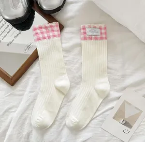 Detail shot of white mid-calf socks with pink gingham cuffs and handmade sewn label.