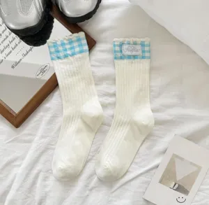 Cute blue and white gingham ruffle cuffs mid-calf socks detail shot, soft cotton material.