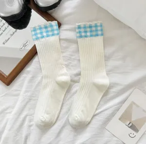 Detail shot of women's blue plaid white mid-calf cotton socks in cozy ins style bed scene.