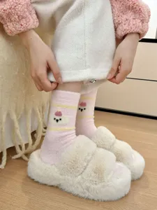 Close-up detail of cozy pink winter plush socks featuring cute cartoon bear pattern and stripes.