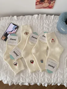 Detailed view of white fluffy winter socks with cute cartoon embroidery, cozy knit texture.
