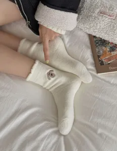 Detail shot of cozy white fluffy fleece socks featuring cute puppy embroidery for warm winter flooring.