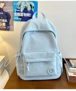 Detail shot of the light blue student casual backpack featuring a front pocket and logo badge.