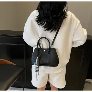 Schwarze minimalistische Damen Umhängetasche, elegante Handtasche mit Anhänger Detail.