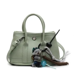 Detailansicht der hellgrünen Leder-Tote-Bag mit stilvollen Henkeln und süßen Anhängern.