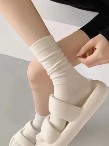 White cotton mid-tube socks detail shot, soft stacking style sock worn with casual chunky slides.