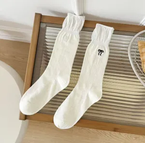 Vista dettagliata con trama a rete e ricamo a fiocco di dolci calze di puro cotone.
