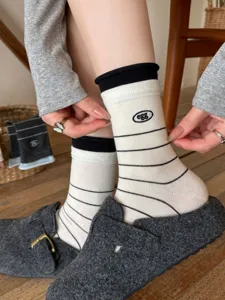 Close-up detail of striped cotton crew socks with cute egg embroidery and classic contrast cuffs.