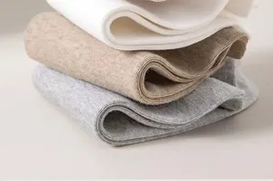 Detailed view of folded cotton ribbed socks in white, khaki, and grey. Soft texture.