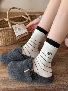 Close-up detail of striped cotton mid-tube socks with cute letter embroidery and black cuffs.