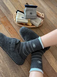 Close-up detail of cozy grey striped mid-calf socks featuring cute letter embroidery.