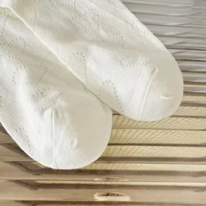 Primo piano dettagliato di calzini di cotone bianco con delicati motivi a cuori estivi.