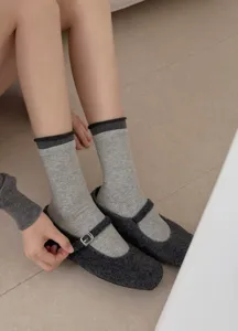 Grey knit crew socks paired with dark grey tweed Mary Jane flats close up detail.