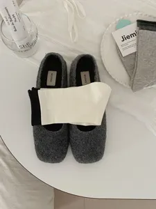 Cozy grey textured flat shoes paired with folded black and white socks in minimalist flat lay.