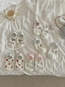 Close-up of cute cartoon pattern cotton boat socks displayed neatly on cozy white bedding.