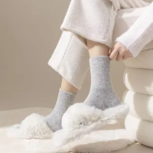 Close-up detail of soft gray wool mid-tube socks paired with fluffy white slippers, cozy style.