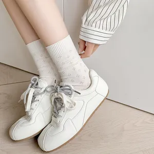 Close-up view of breathable hollow clover mesh mid-tube cotton socks in creamy white tone.