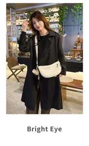 White crescent shoulder bag detail shot with strap and cute pendant in cafe interior.