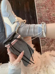 Detailed view of grey ribbon bow socks and ballet-core fashion accessories with stylish aesthetic.