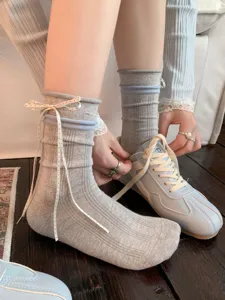 Grey bow crew socks detail showcasing white polka dot ribbon ties and vintage sneakers style.