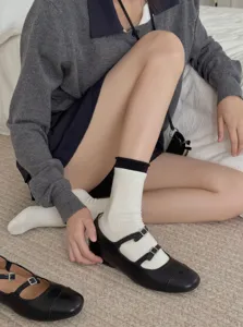 Detail shot of stylish white mid-tube socks with black trim paired with classic black Mary Janes.